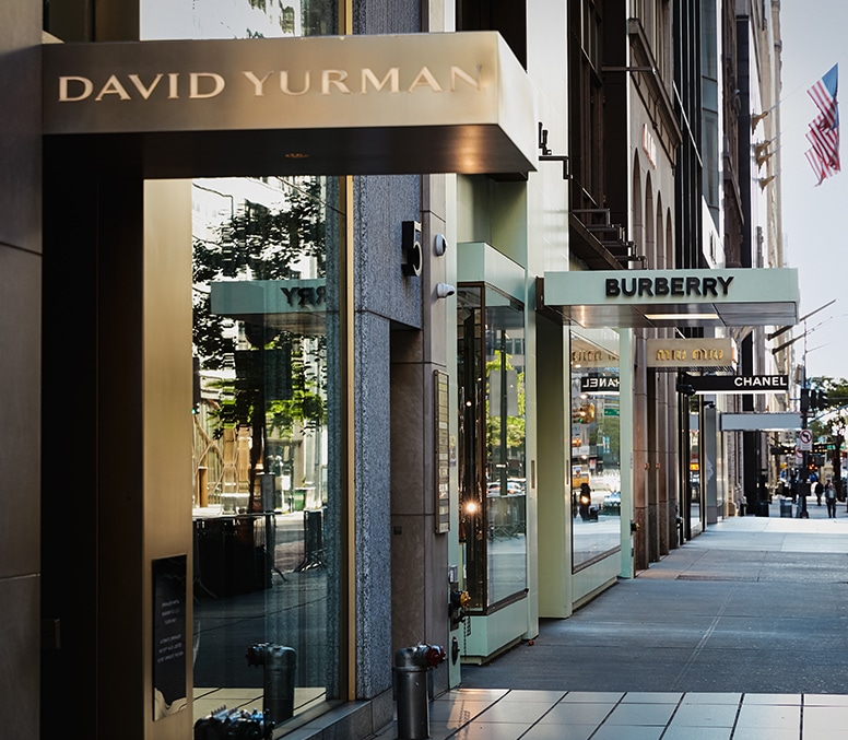 A sidewalk with designer shopping boutiques one after the other